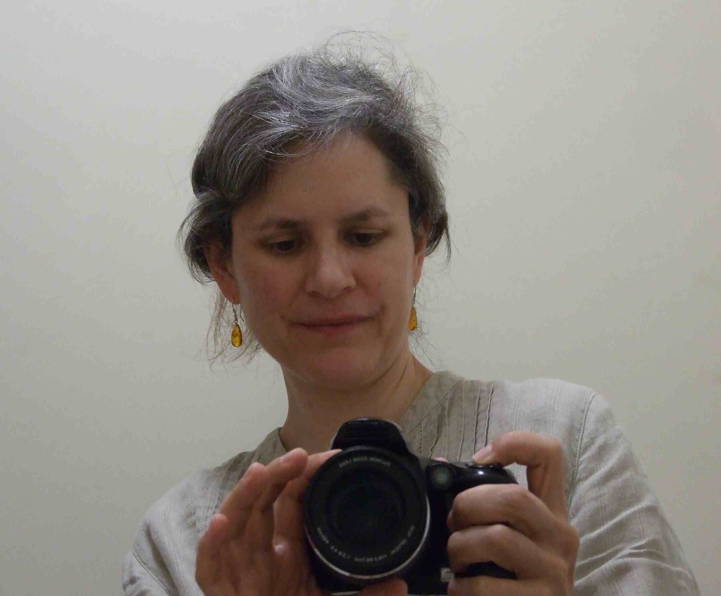 Gabriele Twohig, a female photographer holding a camera, taking a self portrait in the mirror